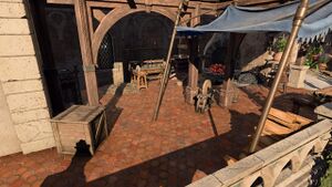 The outside of the Forge of the Nine. A stone patio is equiped with a forge and smithing station.